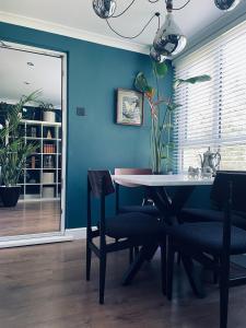 伦敦Luxury mid century Apartment的一间拥有蓝色墙壁和桌椅的用餐室
