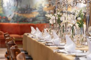 卡斯卡伊斯Palácio Estoril Hotel, Golf & Wellness的一张长桌,上面有白色的餐巾纸和鲜花
