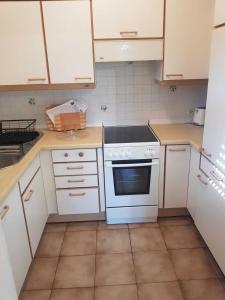 雷宁根L8 Street Apartments - Renningen的厨房配有白色橱柜和炉灶烤箱。