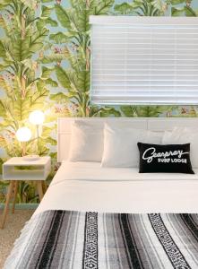 维洛海滩Seaspray Surf Lodge的一间卧室配有一张白色床和热带壁纸