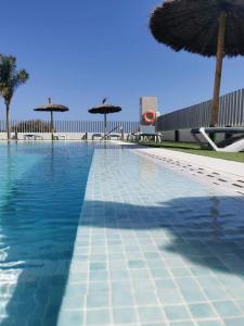 弗拉门卡海滩Turquesa Del Mar - Max Beach Golf - Ground Floor Apartment的一个带遮阳伞和椅子的大型游泳池
