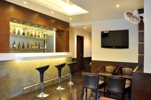 乌代浦Shree Narayana Hotel-BAR-Rooftop Terrace-Disc的酒吧配有黑色椅子和平面电视