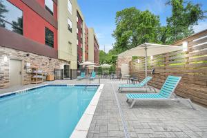 阿什维尔Home2 Suites By Hilton Asheville Biltmore Village的一座带椅子和遮阳伞的游泳池位于大楼旁