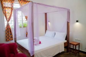 帕杰MOYOWANGU HOUSE PAJE的一间卧室设有天蓬床和窗户。