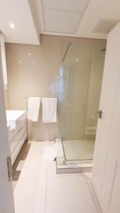 哈博罗内iTowers Studio-Suite的浴室设有玻璃淋浴间,配有毛巾