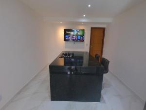 瓦拉达里斯州长市TH 101 - Flat com Banheira de Hidromassagem的厨房配有黑色柜台,墙上配有电视。