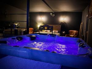 Chazey-sur-AinLoveroom avec jacuzzi 01的配有床的客房内的大蓝色浴缸