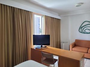 维多利亚Praia do Canto Apart Hotel - Apto 405 - Varanda Lateral com Vista Mar的酒店客房设有一张带显示器和椅子的桌子