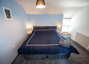 阿博伦The Old Coach House的一间卧室配有一张带蓝色棉被的大床