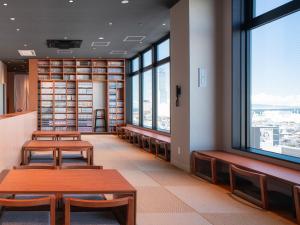 泉佐野REF Kanku-Izumisano by VESSEL HOTELS的图书馆,设有长椅和书架及窗户