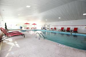 桑达斯基桑达斯基中央希尔顿恒庭酒店的大楼内一个带红色椅子的大型游泳池