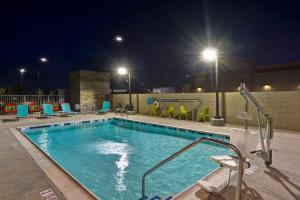 帕姆代尔棕榈谷希尔顿欣庭套房酒店的夜间游泳池,配有椅子和灯