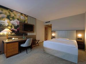 格拉Mercure Hotel Gera City的酒店客房配有一张床、一张书桌和一台电视。