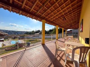 陶巴特Chacara com piscina, churrasq e WiFi em Taubate SP的设有一个配有桌椅并享有美景的阳台。