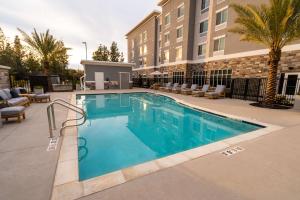 兰乔科尔多瓦Homewood Suites By Hilton Rancho Cordova, Ca的一座带椅子的酒店游泳池,一座建筑