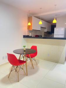 彼得罗利纳Apto Garagem Wifi Condomínio Piscina Ar-condicionado 2 Quartos的厨房配有桌子和四把红色椅子