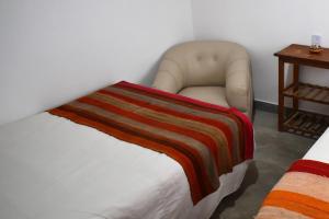 胡阿卡勒拉CASITA MUNAY - Cabaña en Huacalera - Quebrada de Humahuaca - Jujuy的一间卧室配有椅子,床上有毯子