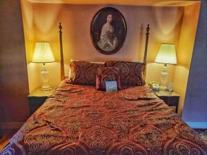 萨吉诺Montague Inn Bed & Breakfast的一间卧室配有一张带两盏灯的床,墙上挂着一张照片