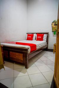 泗水OYO 93069 Penginapan Sumber Rizki的宿舍间内的一张床位,上面有红色枕头