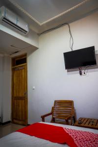 泗水OYO 93069 Penginapan Sumber Rizki的卧室配有一张床,墙上配有电视。