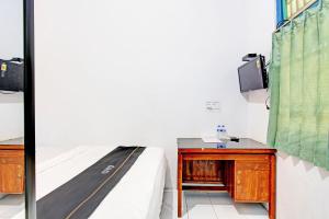 直葛Capital O 92929 Hotel New Tirta Kencana Syariah的一间卧室配有一张床、一张书桌和一台电视。