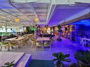 哈林海滩Hideout Hostel的餐厅配有桌椅和紫色照明