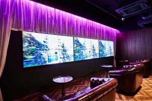 东京Petit Bali Ikebukuro的一间设有紫色窗帘和大屏幕的房间