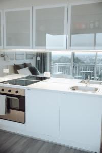 悉尼Cosy studio with a big view的厨房配有白色橱柜、炉灶和水槽。