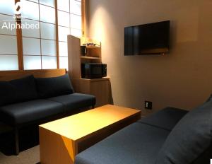 高松ALPHABED INN Takamatsuekimae的带沙发和咖啡桌的客厅