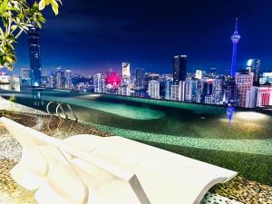 吉隆坡AXON Suites Bukit Bintang By Sky Pool的白色长凳,晚上可俯瞰城市