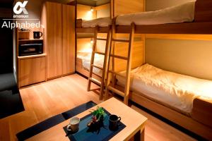 高松ALPHABED INN Takamatsuekimae的小房间设有两张双层床和一张桌子