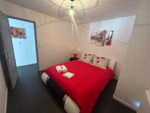 色当Bel appart stylé avec jacuzzi的一间卧室配有红色的床和2条毛巾