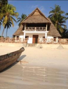 江比阿The Loft Zanzibar Kikadini Beach的海滩上的一座建筑,在水中划船