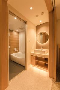 札幌Hotel Emion Sapporo的带浴缸、水槽和镜子的浴室