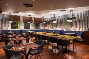 迪拜Premier Inn Dubai Al Jaddaf的一间在房间内配有桌椅的餐厅