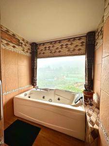 梅萨隆ดอยหมอกดอกไม้รีสอร์ท DoiMok DokMai Resort的带浴缸的浴室和大窗户
