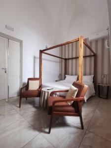 莱切Dimora San Biagio Suites&Apartment的一间卧室配有一张床和几把椅子