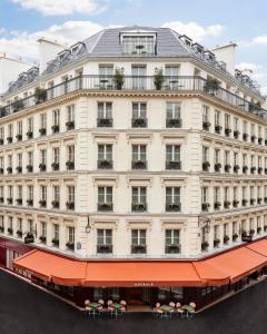 巴黎Le Grand Mazarin的一座白色的大建筑,有红色遮阳篷