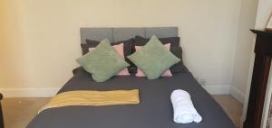 考文垂Coventry Spacious Rooms In City的一张带粉色和绿色枕头的床,床上有毛巾
