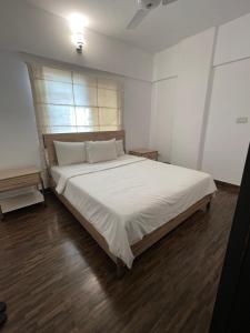 卡拉奇Ghumo - DHA Near Sea View Serviced Apartments的一间卧室配有一张带白色床单的大床