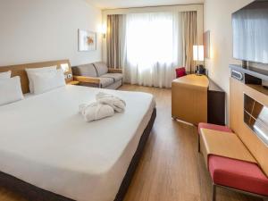 萨莱诺诺富特萨雷诺伊斯特雷其酒店的酒店客房设有一张白色大床和一张沙发。