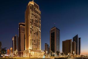 多哈Wyndham Grand Doha West Bay Beach的城市天际线,夜晚有高耸的摩天大楼