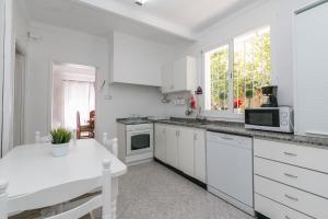 帕尔马海滩Villa los brezos的白色的厨房配有白色橱柜和白色桌子