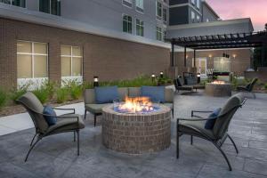 格林维尔Homewood Suites By Hilton Greenville, NC的一个带火坑和椅子的庭院和一座建筑