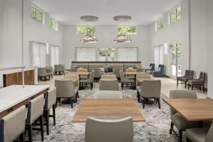 格林维尔Homewood Suites By Hilton Greenville, NC的一间设有桌椅和窗户的等候室