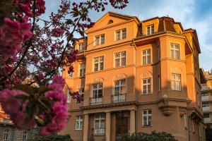 卡罗维发利唯高夫公寓的一座大型橙色建筑,设有窗户和粉红色的鲜花
