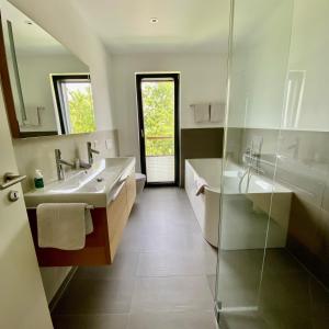 SalensteinFeWo Bodenseewest的一间带两个水槽和玻璃淋浴间的浴室