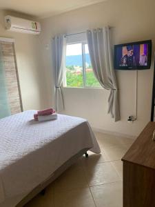 廷博Pousada Guesthouse的一间卧室设有一张床和一个带电视的窗户。
