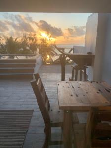 马特姆维Zi Loft Beach Cottage的阳台上的木桌和长凳享有日落美景