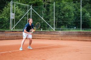 Mönichwald加斯特伍德夏夫特霍尔德酒店的网球运动员在网球场上手持网球拍